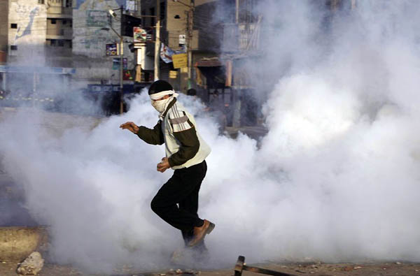 Mahalla, Egypt: A protester runs from tear gas during an anti government demonstration