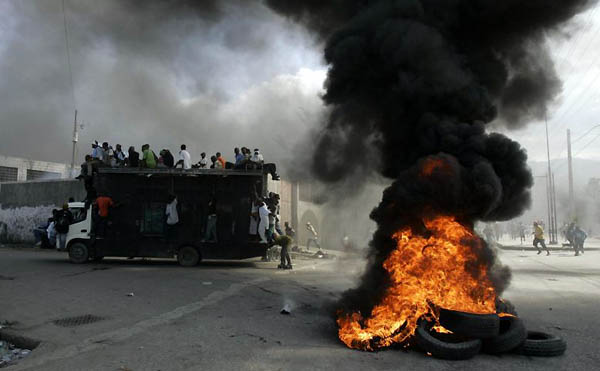 Port-au-Prince: A truck drives past a burning barricade during an anti-government demonstration