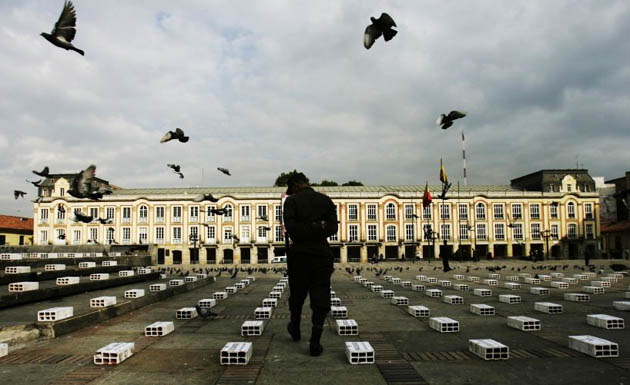 A police officer looks at bricks with the names of the victims of violence in Colombia written on them at Bolivar square