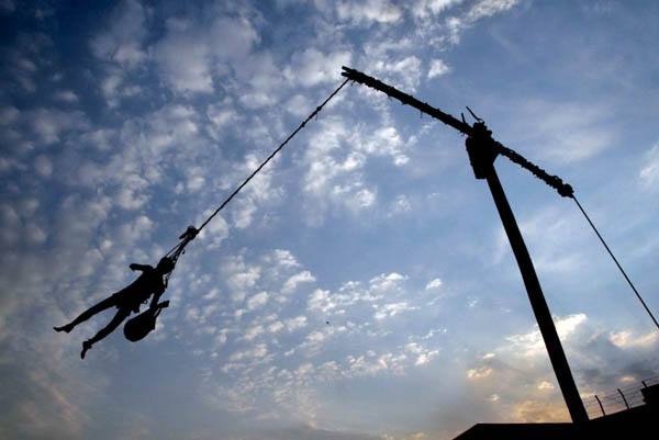 Calcutta, India: A Hindu holy man hangs on a rope that is attached to a holy pillar during the Gajan festival on the eve of Bengali New Year