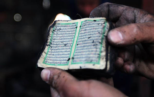 Baghdad, Iraq: A resident displays a charred Quran after a shop burned down. Several shops at the market in eastern Baghdad were set on fire after a road side bomb struck a US humvee vehicle