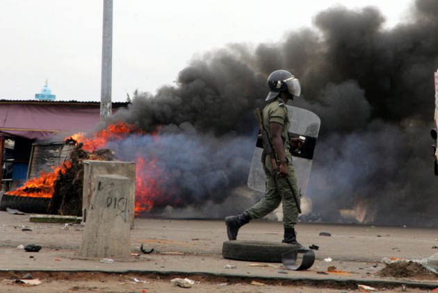 A police officer walks past a burning road block in Port Bouet, Ivory Coast