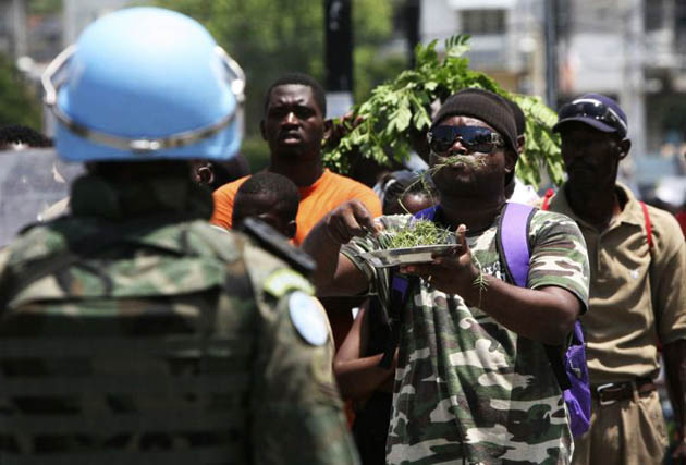 A demonstrator eats grass in front of a U.N. Brazilian peacekeeping soldier in Port-au-Prince, Haiti