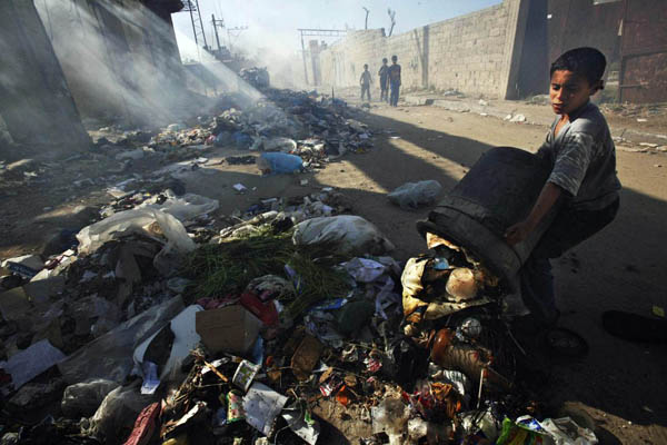 Gaza City, Gaza Strip: Smoke rises from burning rubbish overflowing onto a residential street