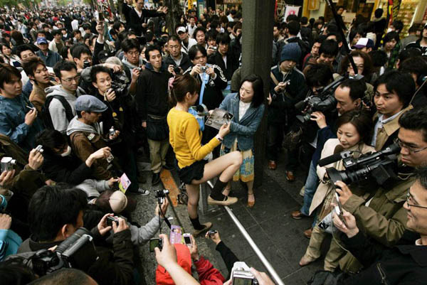 Tokyo, Japan: A street performer is surrounded by amateur photographers and spectators while she is interviewed by local TV reporters during a promotion for the 'maid cafe' in which she works for as a waitress