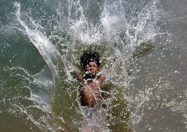 Bhubaneshwar, India: A boy splashes into an irrigation canal to beat the summer heat