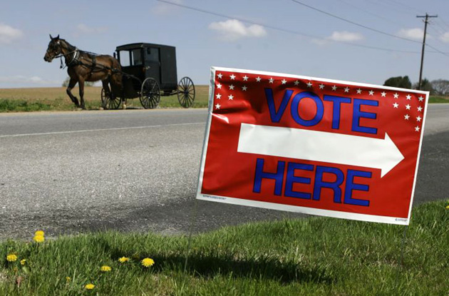 An Amish horse and buggy roll past a polling station