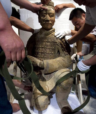 Workers prepare to put a Terracotta warrior into a crate for shipment to the United States