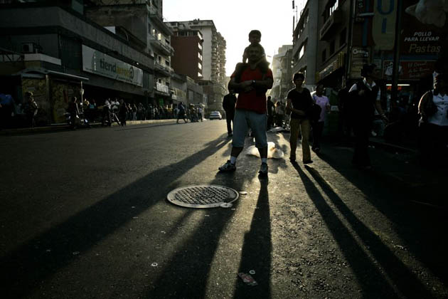 Pedestrians walk as they wait for public transportation outside a subway station in Caracas