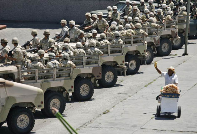 A man sells snacks as Mexican soldiers prepare to patrol after a meeting of high ranking city, state and federal security officials in Tijuana, Mexico