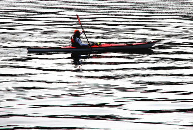 A kayaker paddles through the striped water of Dyes Inlet near Bremerton