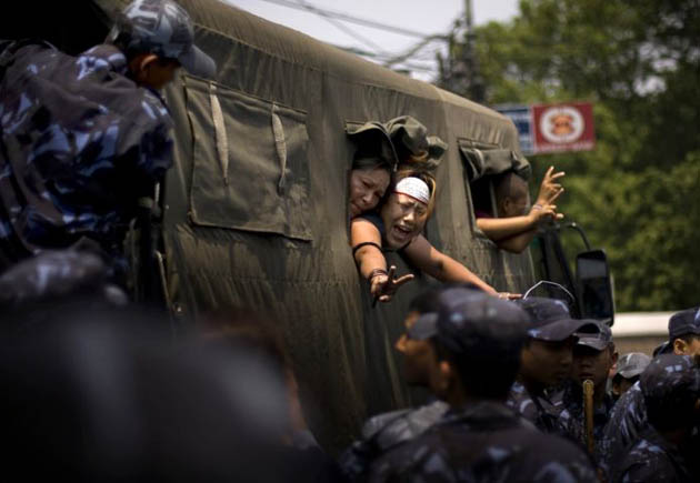 Tibetan demonstrators shout from a police van as they are detained by Nepalese police officers during a protest outside the Chinese consulate