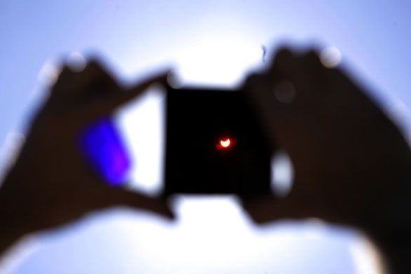 Riga, Latvia: A man uses a special filter to observe a partial solar eclipse