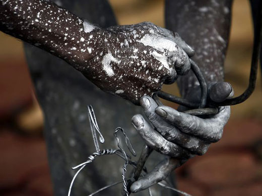 Mumbai, India: A worker ties a cable onto boxes while painting a light pole