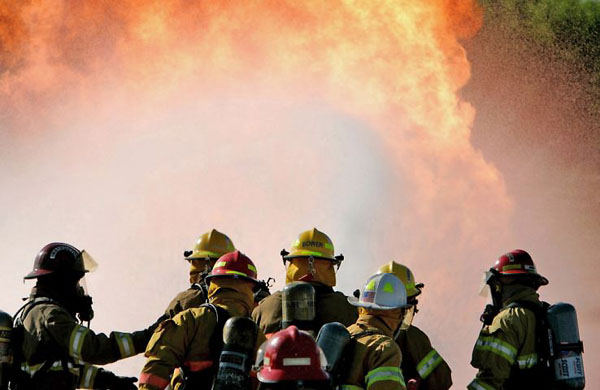 Grand Island, US: Instructor Todd Brim and volunteer firefighters advance toward a propane 'christmas tree' to practice pushing flames away from a valve
