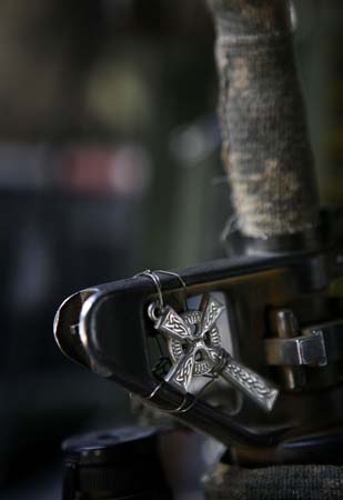Captain Workman, 101st Airborne division hangs his cross on his gun