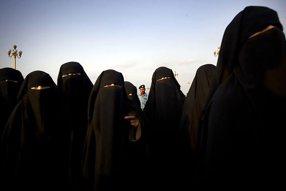 Islamabad, Pakistan: A police officer stands behind women taking part in rally calling for the release of Aafia Siddiqui