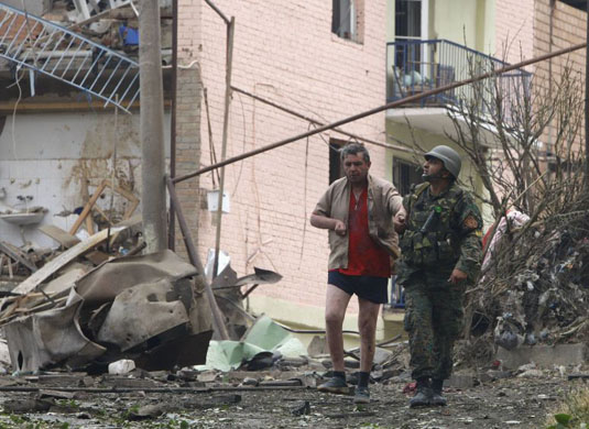A Georgian soldier helps a wounded man in Gori