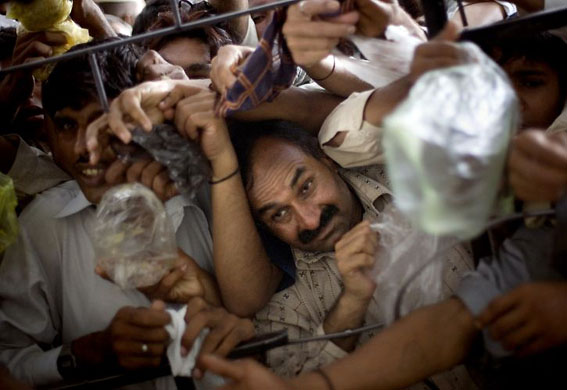 Lahore, Pakistan: Men struggle as they try to get their ration at a donated food distribution