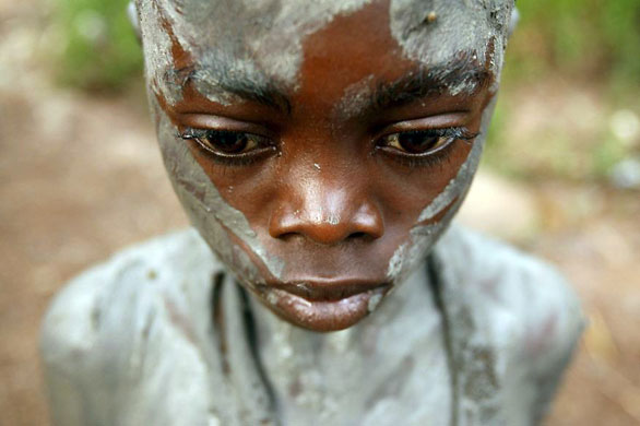 Bungoma, Kenya: Ben Wanjala stands at the rivers edge after being smeared with clay during a circumcision ceremony