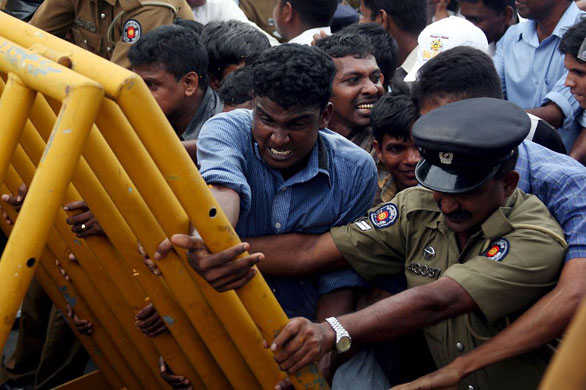 Colombo, Sri Lanka: Protesting unemployed graduates attempt to push down a barrier
