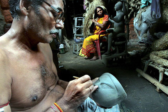 Calcutta, India: Artist Nilkanta Pal works on unfinished clay idols of Goddess Durga