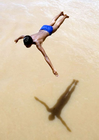 Phnom Penh, Cambodia: A boy dives into the swollen water of the Tonle Sap river