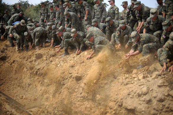 Georgian soldiers throw dirt into a mass grave