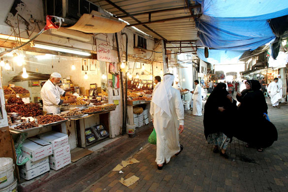 Kuwaitis walk past a vendor displaying dates at a market