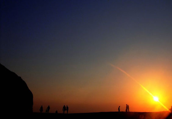 Paphos, Cyprus: People walk on the beach during sunset at 'Petra tou Romiou'