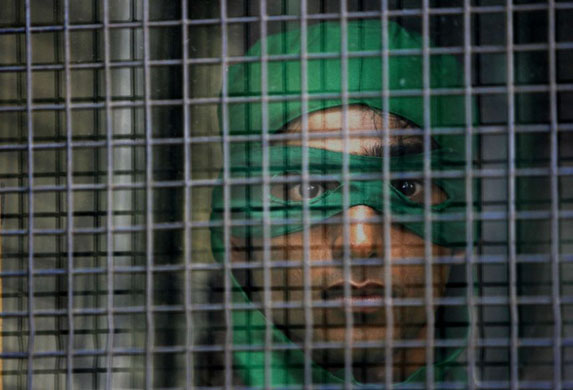 Mumbai, India: A detained Greenpeace activist dressed as a turtle looks out from a police van