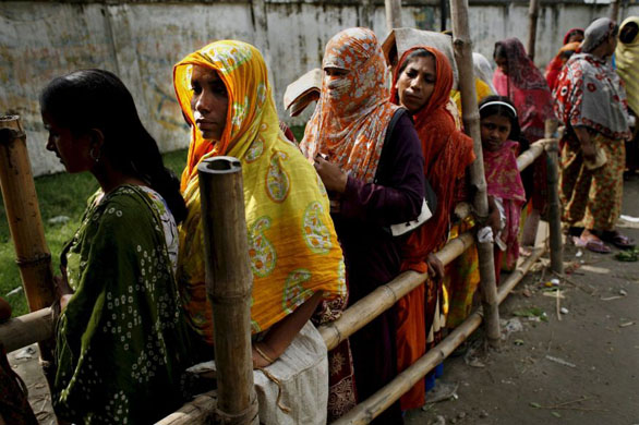 Dhaka, Bangladesh: People of low income groups stand in queue at a shop to buy rice at subsidized price