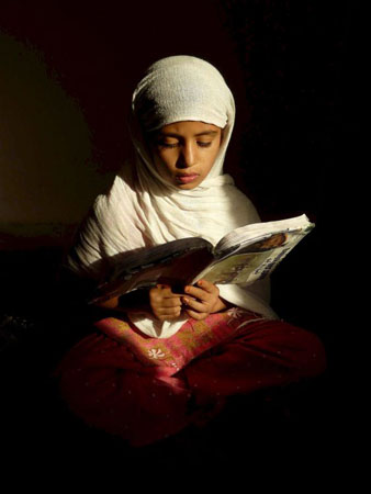 Kabul, Afghanistan: A girl reads a school book at her home