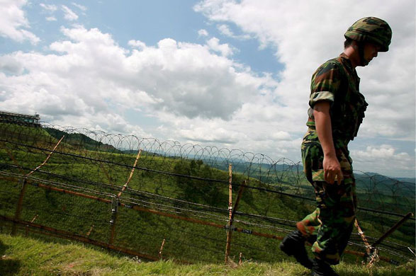 Gyeonggi province, South Korea: A military policeman patrols a barbed-wire fence on the demilitarized zone separating North Korea from South Korea