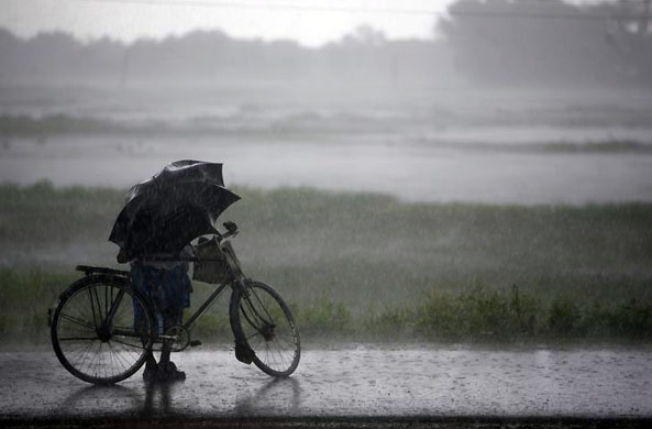 Singur, India: A farmer tries to protect himself from heavy rain