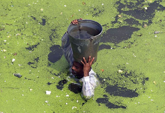Lucknow, India: A man carries drinking water through a flooded street