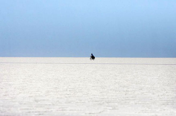Salar de Uyuni, Bolivia: A man rides a bicycle on the surface of the world's largest salt flat