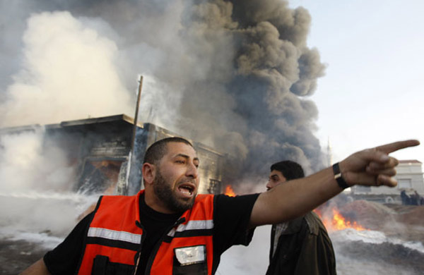 A Palestinian firefighter shouts in front of a burning building following an Israeli air strike in the Gaza Strip