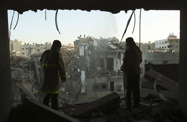 Palestinians inspect the building of Hamas TV destroyed following an air strike