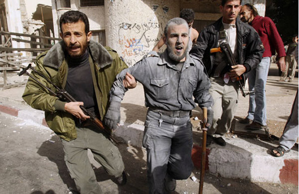 A wounded Hamas policeman is helped by his colleagues following an Israeli air strike at the main Hamas security complex in Gaza