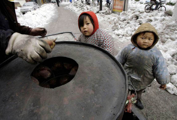 Two local children look at a sweet potato vendor in Nanjing