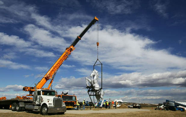 Construction workers install a mustang sculpture at the international airport