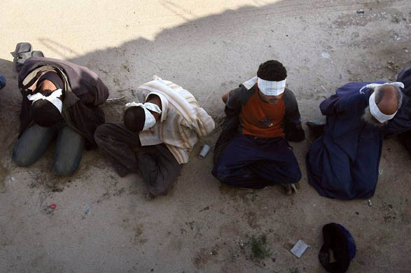 Palestinian prisoners sit blindfolded on the ground after they were captured by Israeli soldiers