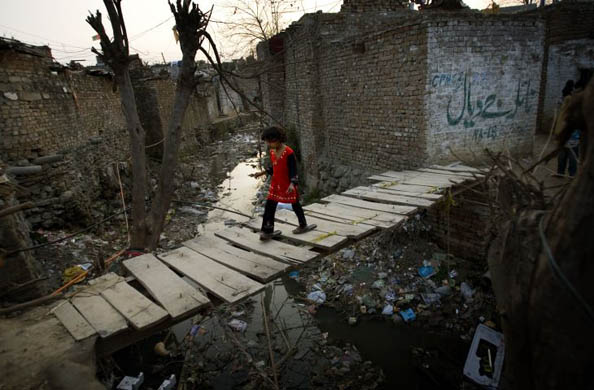 Islamabad, Pakistan: A girl crosses a wooden bridge