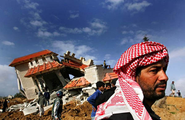 Palestinians inspect a house destroyed by Israeli bulldozers and tanks