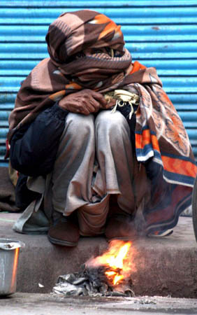 A shopkeeper warms himself by a fire