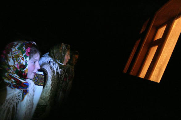 Girls sing Christmas carols near a window