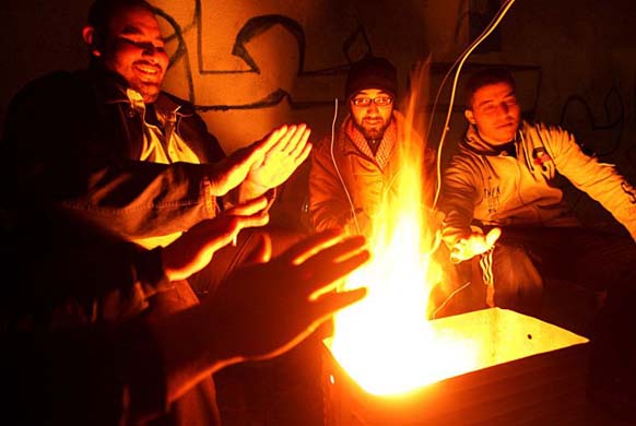 Palestinian men sit around a fire