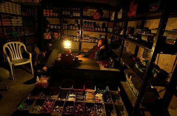Palestinian men in their shop surrounded by gaslight in Gaza