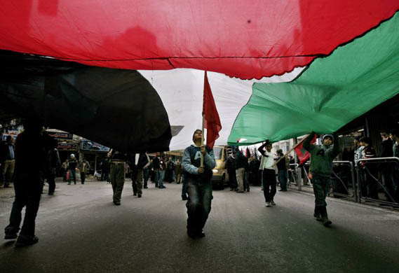alestinians carry a huge flag during a rally to mark the death of George Habash